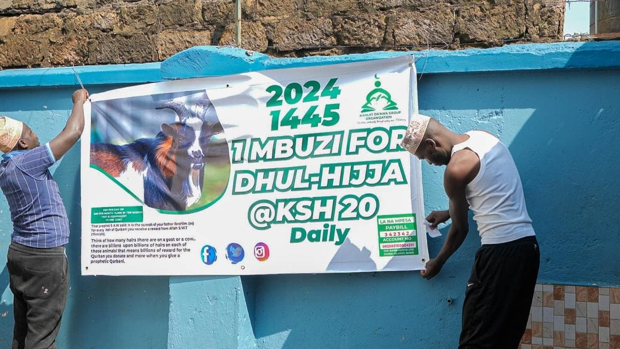 Two men fastening a banner for the 2024 Dhul Hijja appeal: one mbuzi at KSh 20 a day.
